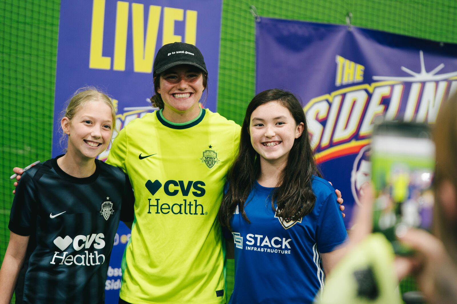 Kate Wiesner smiling with two young players for a group photo after the event.