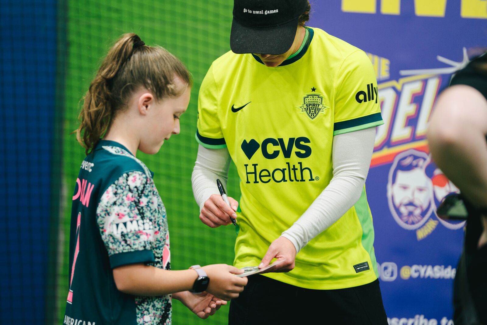 Kate Wiesner signing an item for a young player after the event.